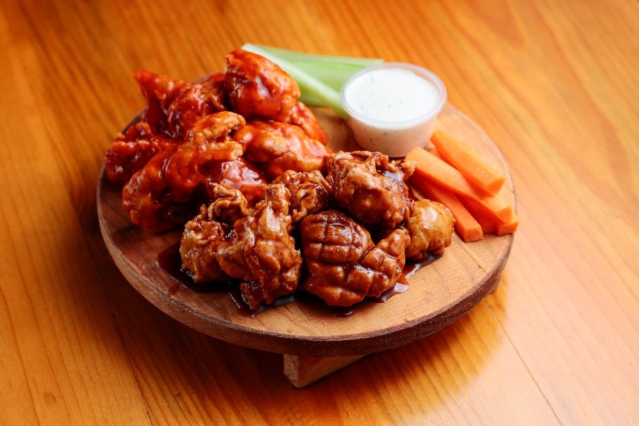 Crispy golden air fryer chicken wings piled high with dipping sauce.