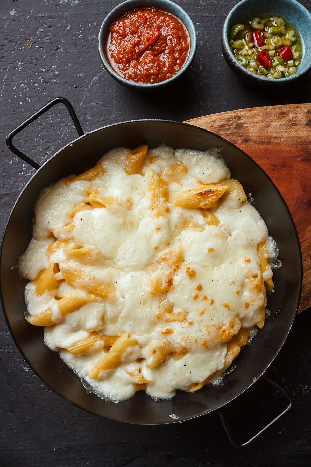 Baked ziti with bubbling cheese and marinara in a casserole dish.