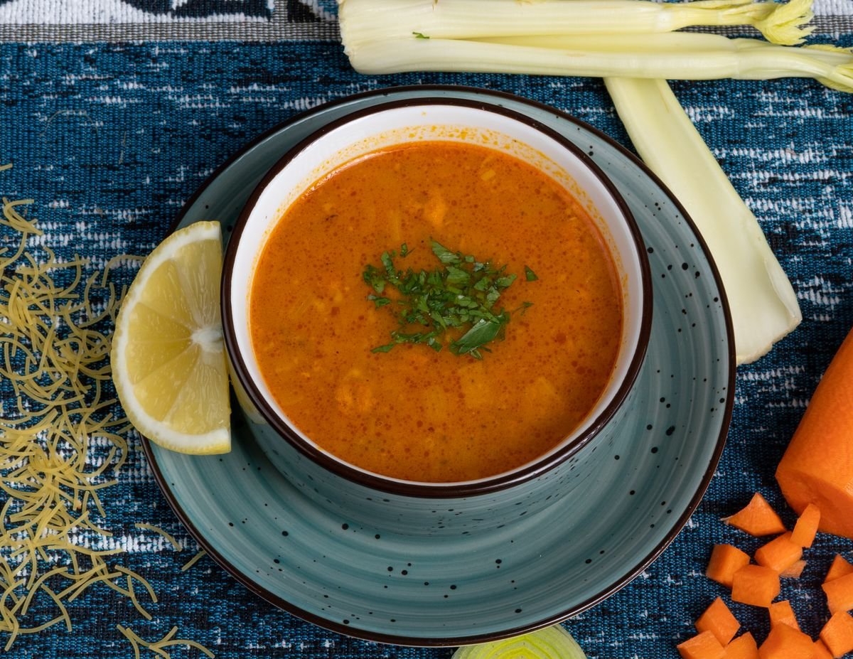 A bowl of golden red lentil soup with a swirl of cream and fresh herbs.