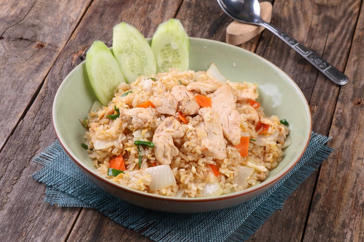 A wok of golden chicken fried rice with peas, carrots, and scrambled egg.