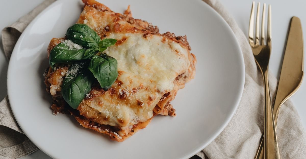 Baked lasagna rolls in a tray topped with melted cheese and marinara.