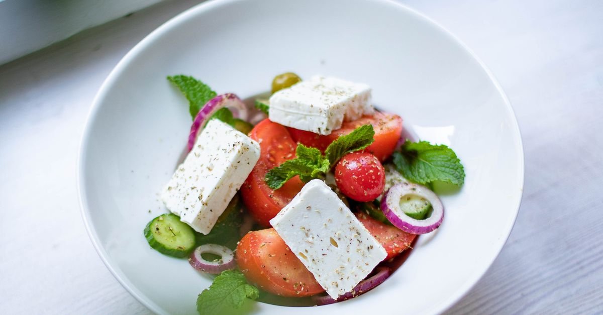 A Greek chicken bowl with feta, olives, cucumbers, and fresh vegetables.