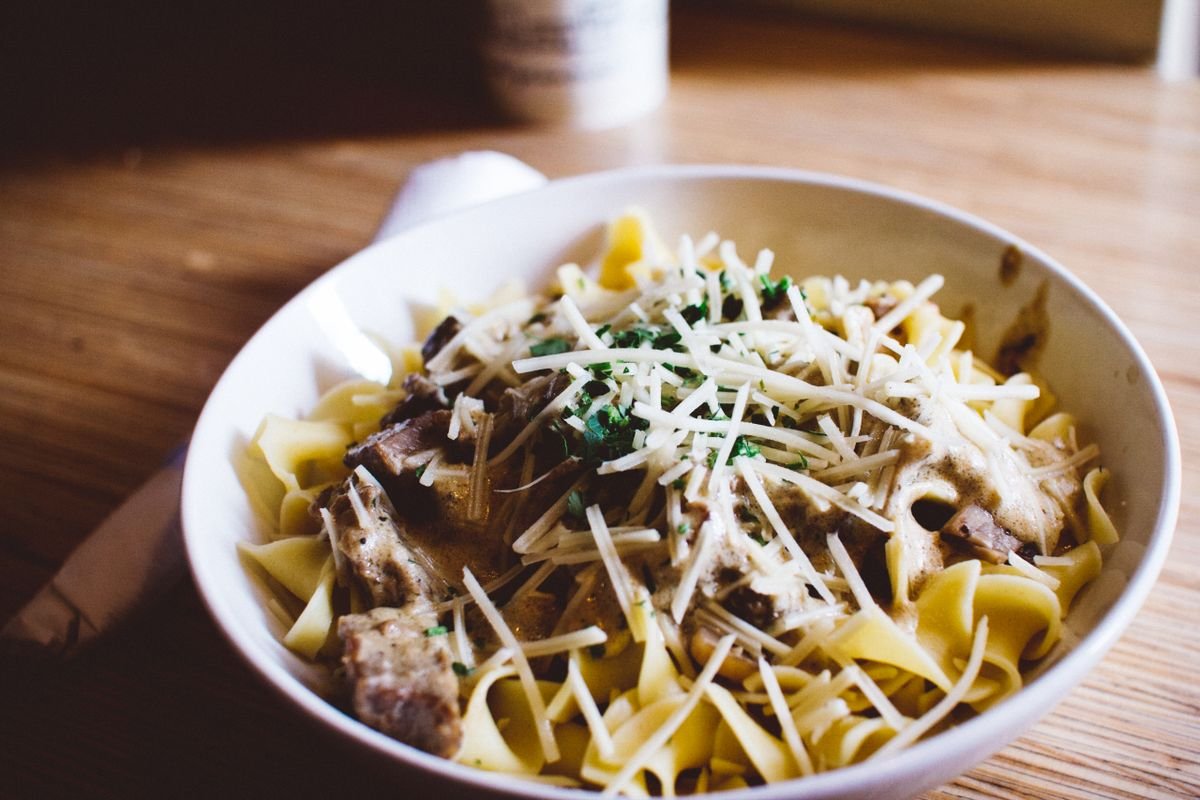 A bowl of creamy garlic parmesan pasta topped with grated parmesan and herbs.