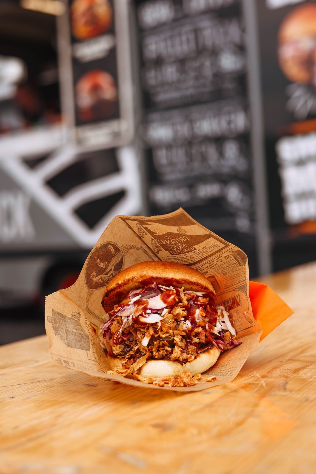 A pulled pork sandwich with coleslaw on a wooden table.